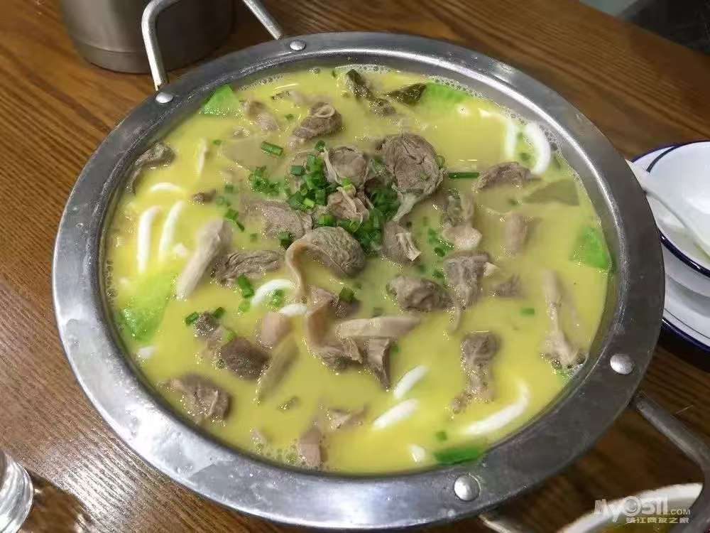 厨师正在厨房精心烹制鱼头泡饼，展现对烹饪过程的专注